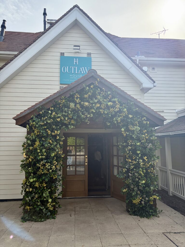 Flower-covered entrance porch below the Outlaw House sign at Canford Cliffs