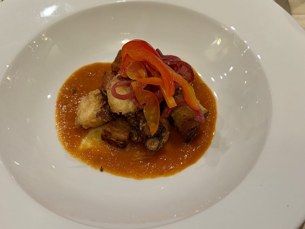 Crispy pork belly and octopus on red pepper ketchup, topped with pickled peppers and red onion