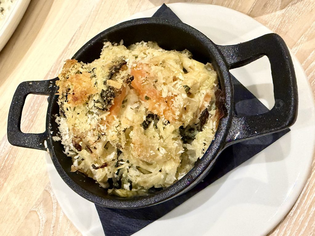 Fennel, cabbage and carrot gratin with a crumb topping, in a small black cast-iron dish