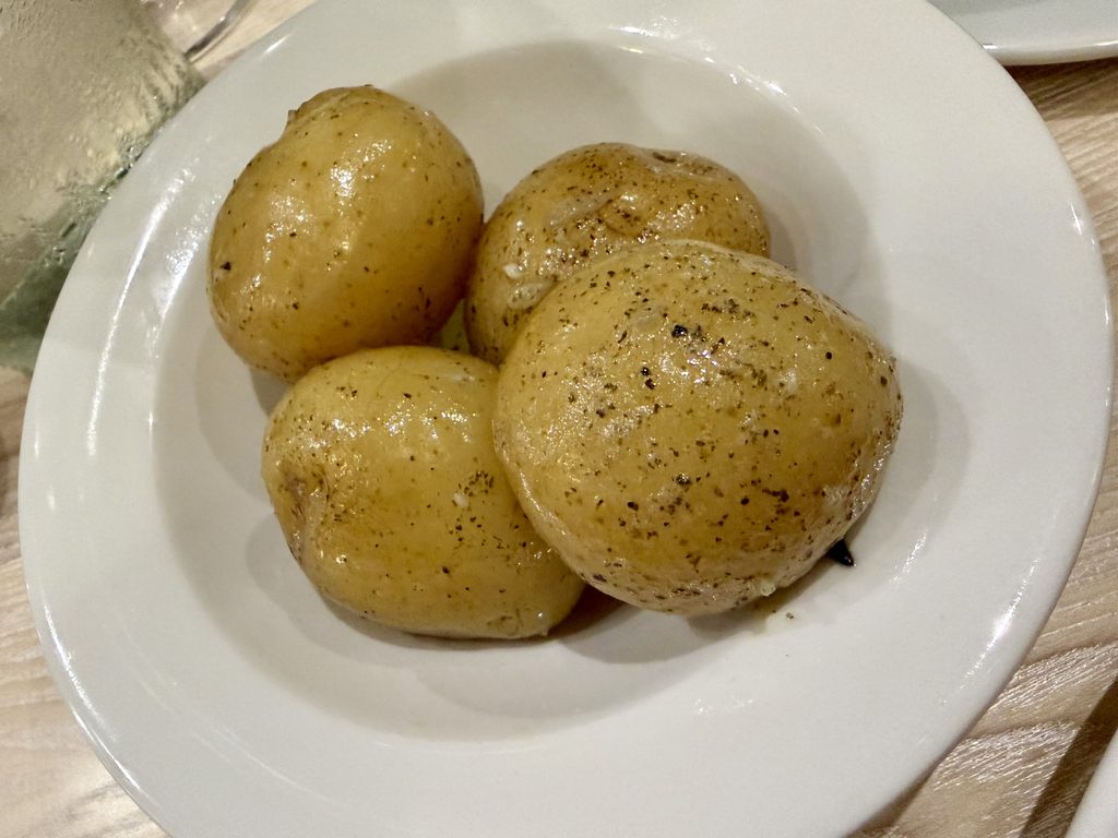 Cornish mids, small new potatoes in seaweed butter, served in a white bowl