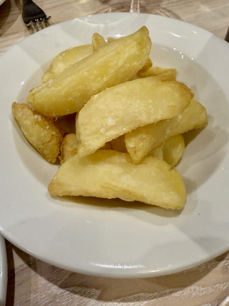 A bowl of thick hand-cut chips sprinkled with flaky sea salt